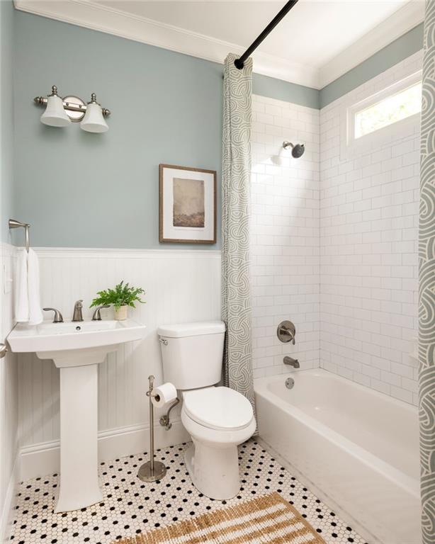 Bathroom with a pedestal sink, subway-tile tub surround, and black-and-white mosaic floor.