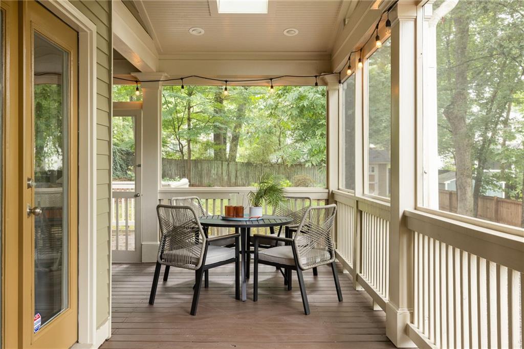 Screened porch with outdoor dining set, string lights, and leafy backyard views.