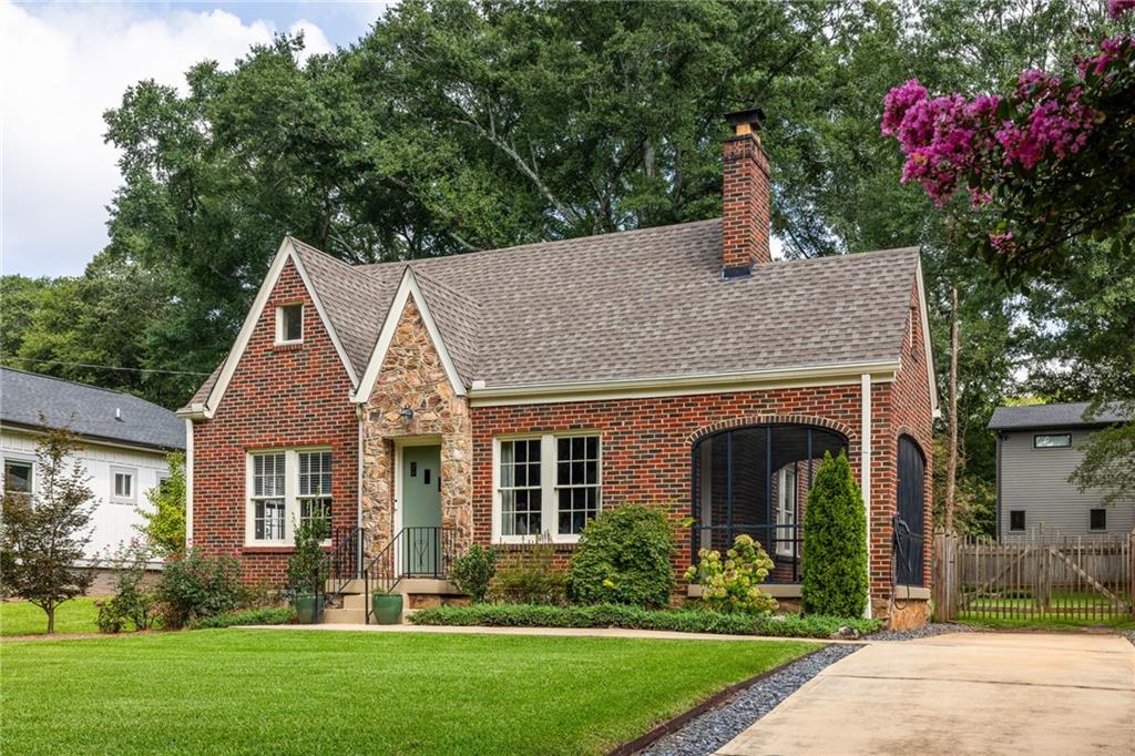 Red-brick home with a stone entry, arched screened porch, and broad front lawn.