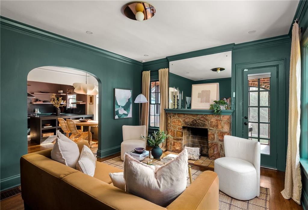 Living room with deep green walls, a stone fireplace, and a mustard sofa.