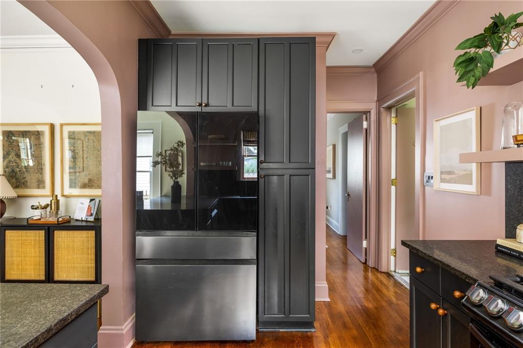 Kitchen with a stainless-steel refrigerator set into charcoal cabinetry, pink walls, and hardwood floors.