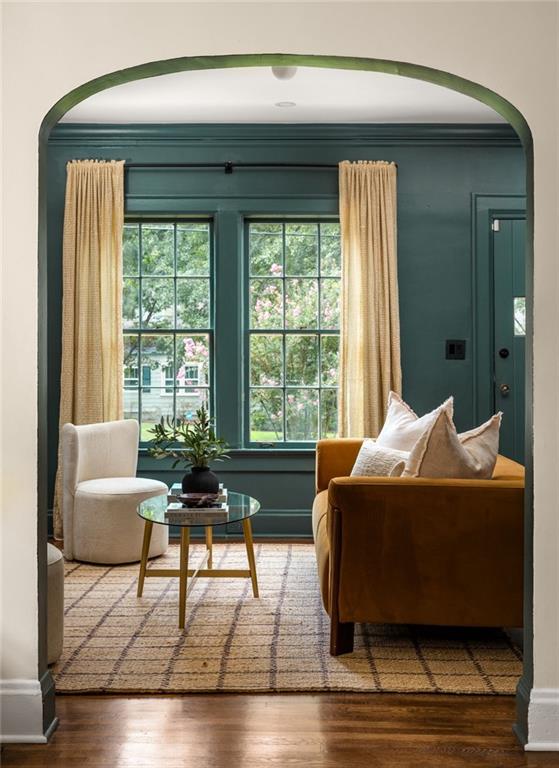 Living room with teal walls, tall curtained windows, and a caramel sofa.