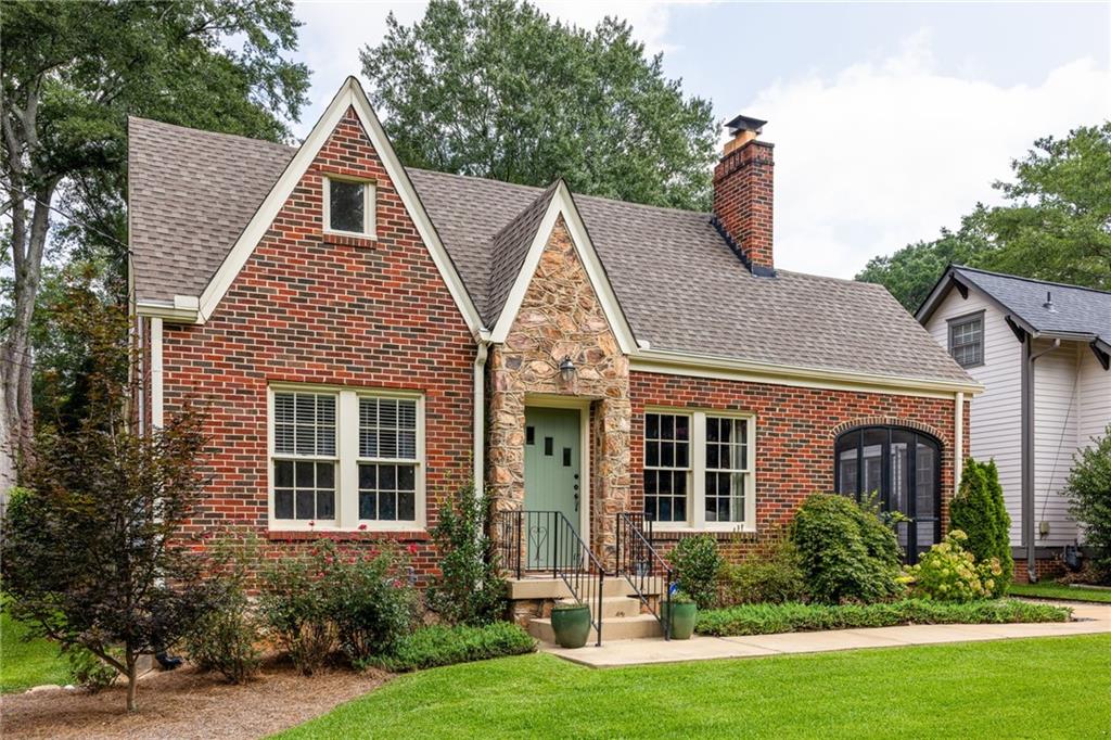 Red-brick home with steep gables, a stone entrance, and a landscaped front lawn.