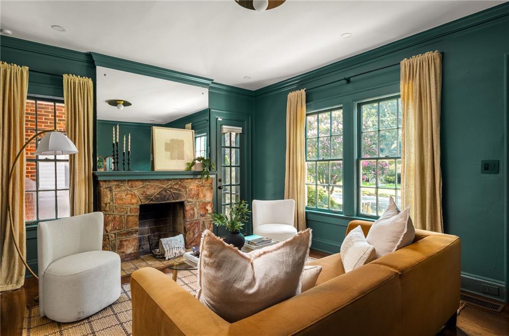 Living room with teal walls, a stone fireplace, and large curtained windows.