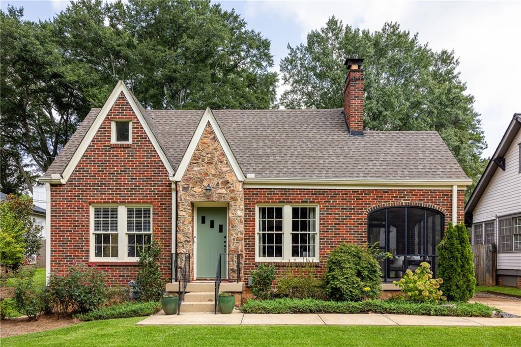 Red-brick home with a stone entry, steep gables, and a screened porch.