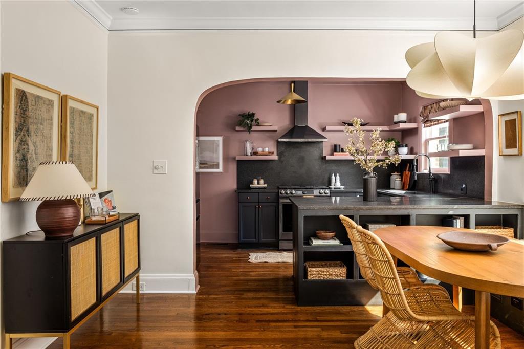 Kitchen and dining area with a mauve arched alcove, dark island, and wicker chairs.