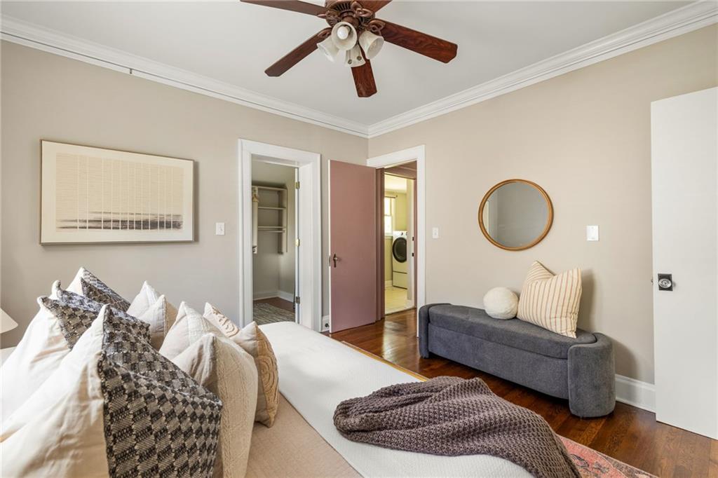 Bedroom with a layered bed, gray bench, ceiling fan, and open doors to a closet and laundry area.