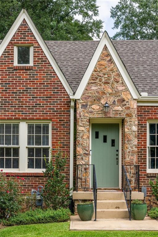 Brick house with steep gables, a stone entry, and a pale green front door.