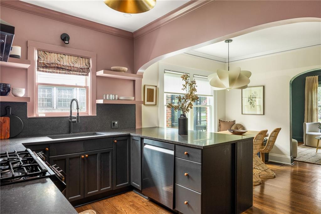 Kitchen with dark cabinets and a large island, opening through an arch to a dining area.