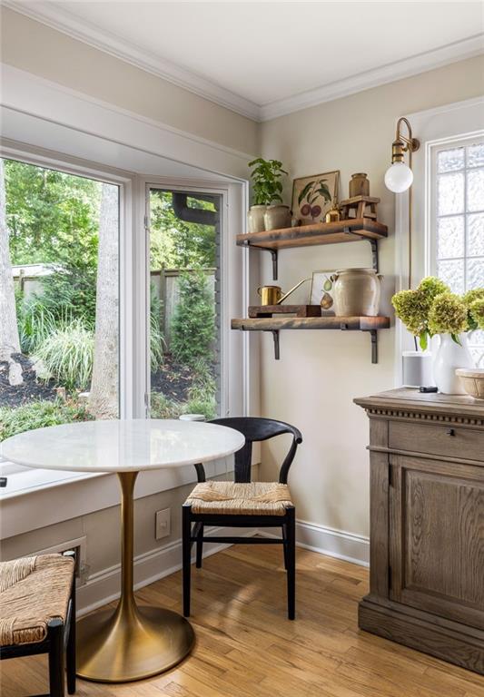 Dining nook with a round white table, black chairs, and windows overlooking a leafy garden.