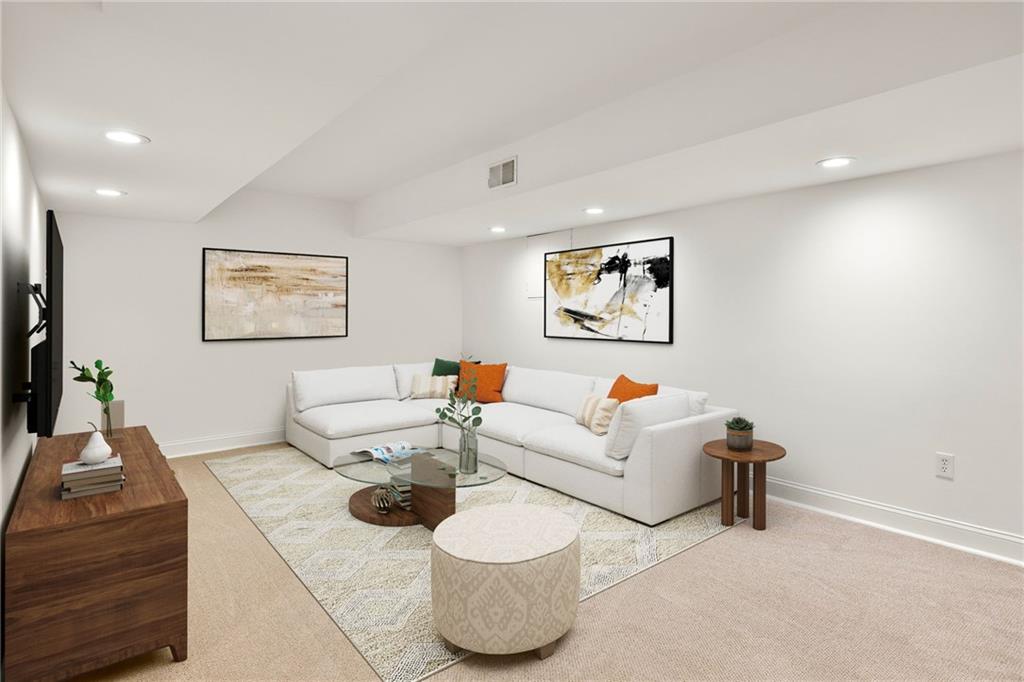 Staged living room with a white sectional, orange pillows, abstract art, and a glass coffee table.