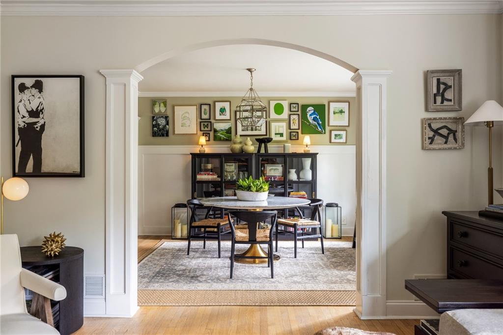 Dining room with a round table and chandelier framed by a broad white archway.