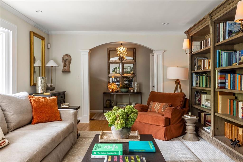 Living room with a built-in bookcase, arched alcove, gray sofa, and rust-colored armchair.