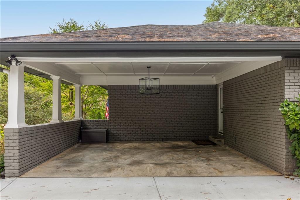 Covered brick carport with white columns and a hanging light fixture.