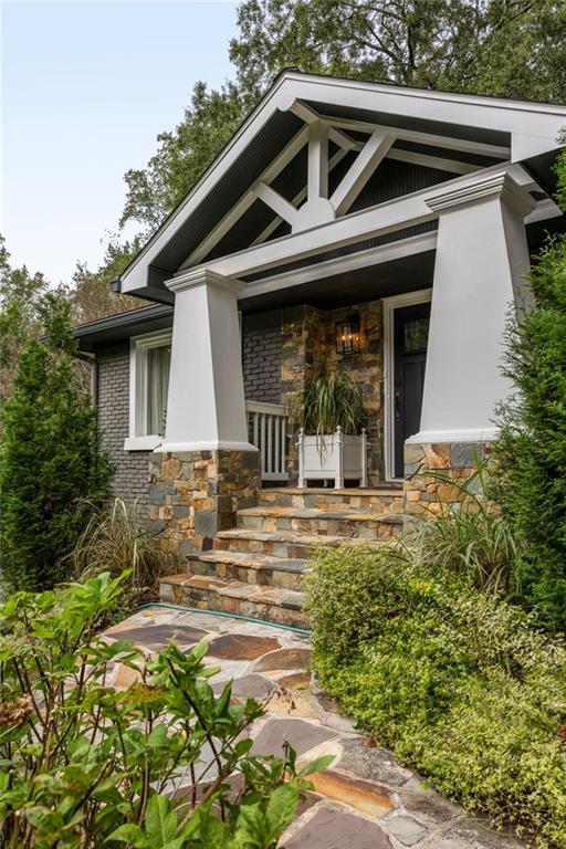 House entrance with white gable trusses, stone steps, and landscaped greenery.