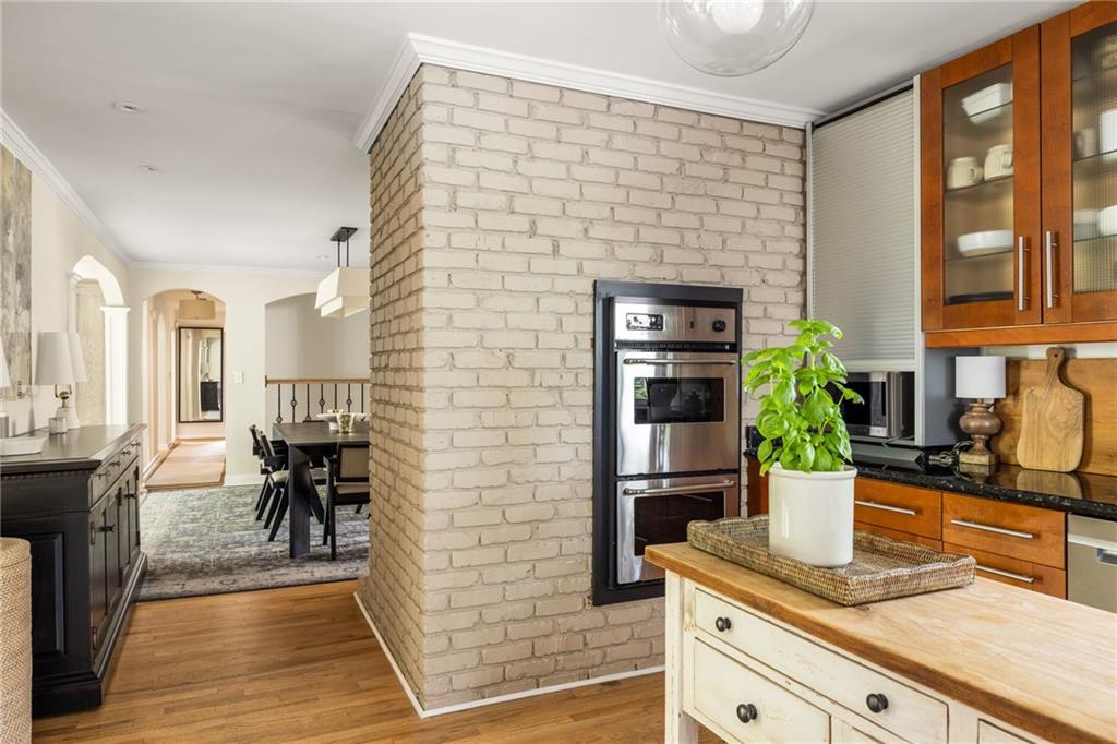 Kitchen with a white brick oven column, warm wood cabinets, and a pale wood-topped island.