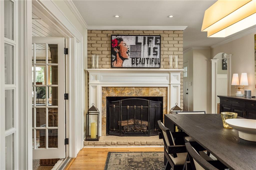 Dining room with a brick-backed fireplace, white mantel, and long dark wood table.