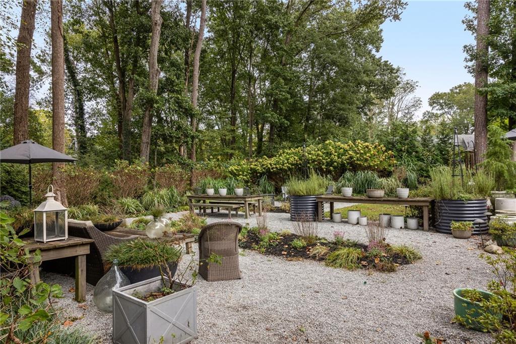 Gravel garden patio with outdoor seating, raised planters, and mature trees.