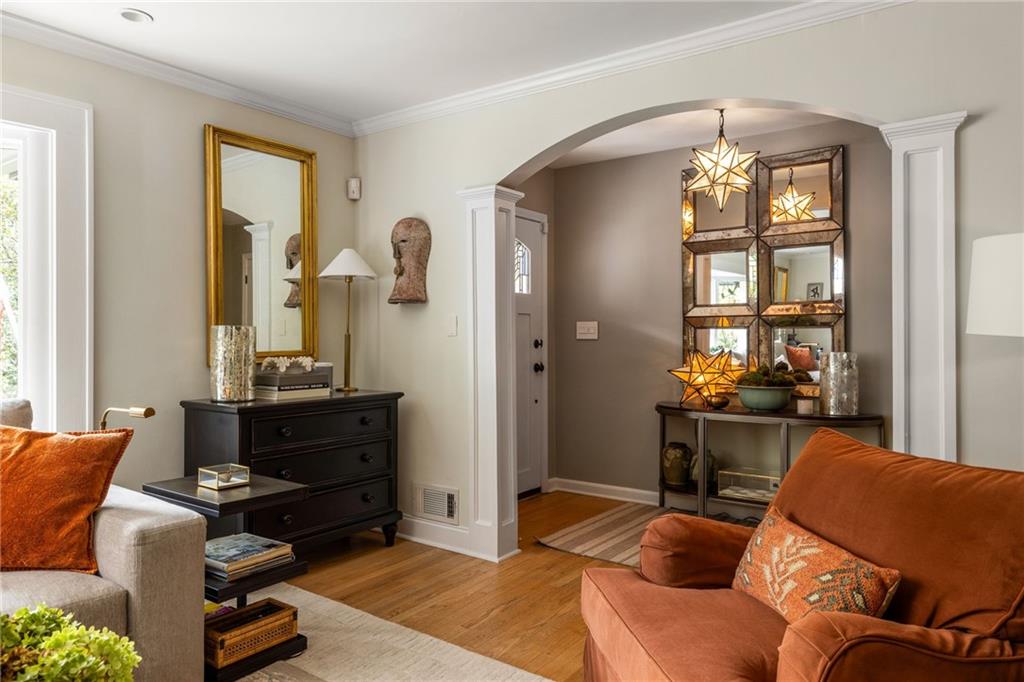 Living room with an arched entry, mirrored console, star pendant lights, and rust-colored sofas.