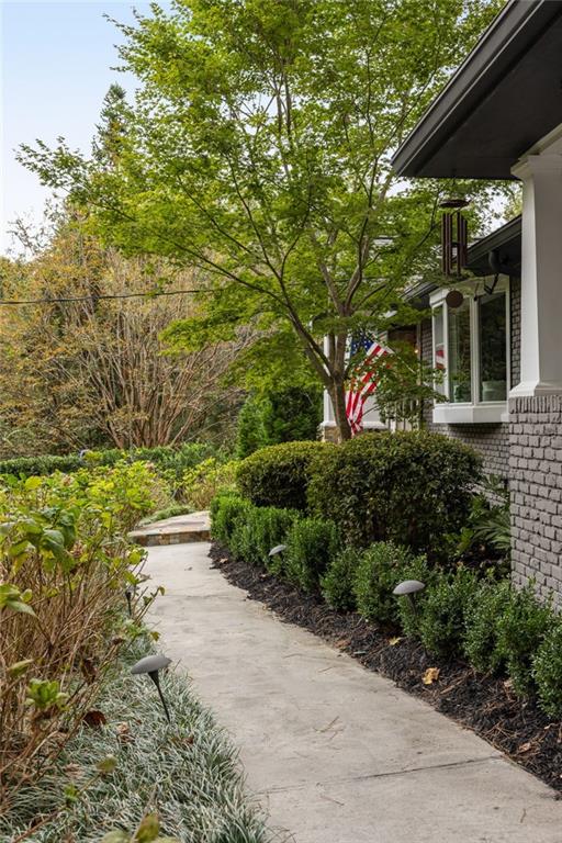 Landscaped walkway leading to a brick home, with an American flag beside the windows.