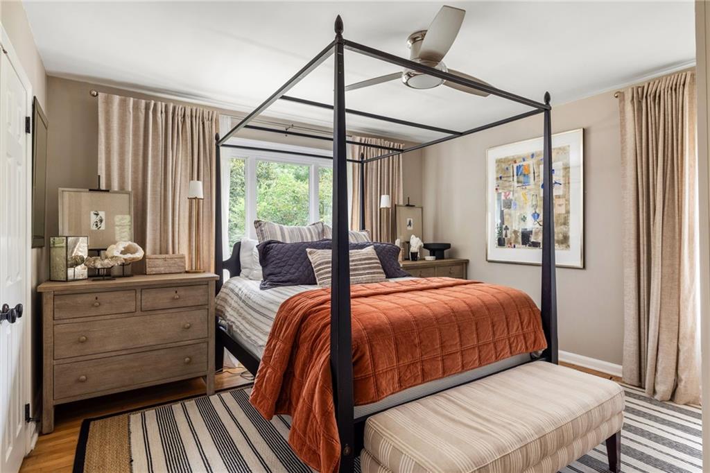 Bedroom with a black canopy bed, rust-colored quilt, and upholstered bench at its foot.