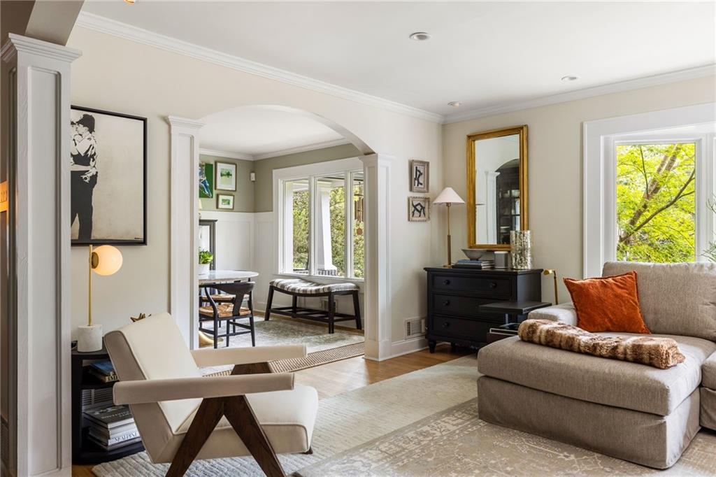 Living room with a beige sectional, cream lounge chair, and arched opening to the dining area.