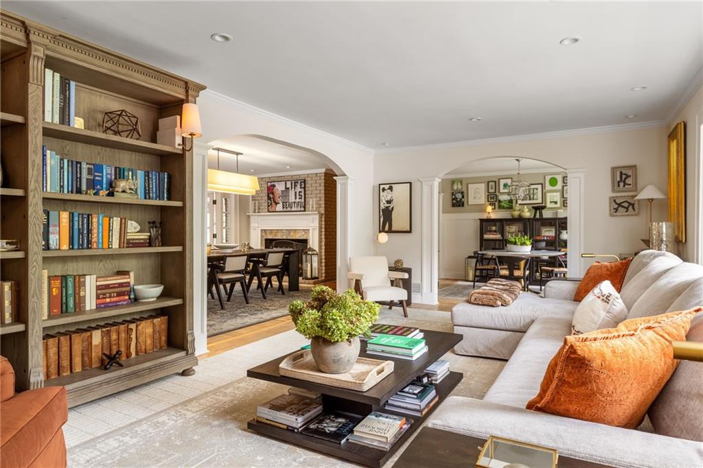 Living room with a built-in bookcase, white sectional, orange cushions, and arched openings to adjoining rooms.