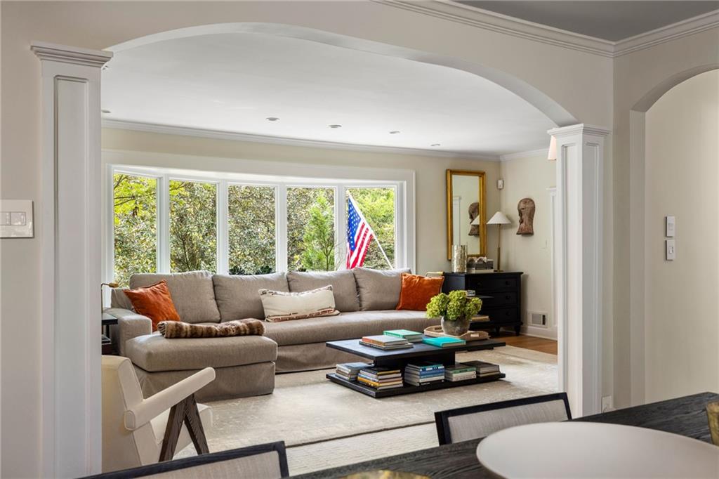 Living room with a gray sectional, large windows overlooking greenery, and an American flag.