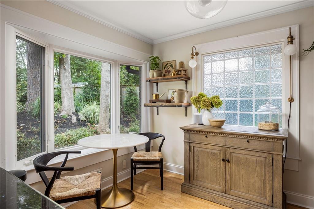Breakfast nook with a round table, garden-facing windows, and a wooden cabinet.