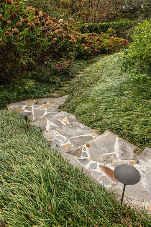 Flagstone garden path winding between ornamental grasses and flowering shrubs, with low path lights.