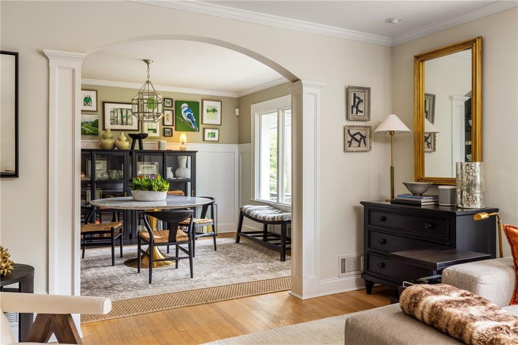 Furnished living room opening into a dining area with a round table and dark display cabinets.