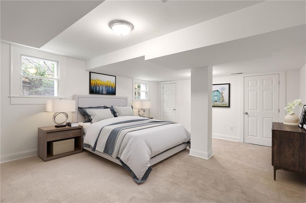 Staged bedroom with a large white-and-gray bed, beige carpet, and two windows.