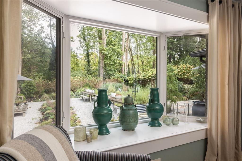 Window nook with green ceramic vases overlooking a landscaped garden and gravel patio.