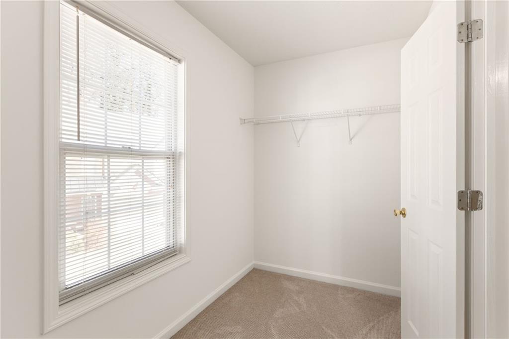 Empty carpeted closet with a window and wire shelf.