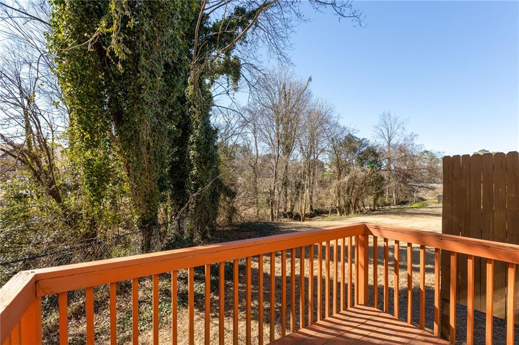 Wooden deck overlooking a leaf-strewn yard and wooded area, with a privacy fence on the right.