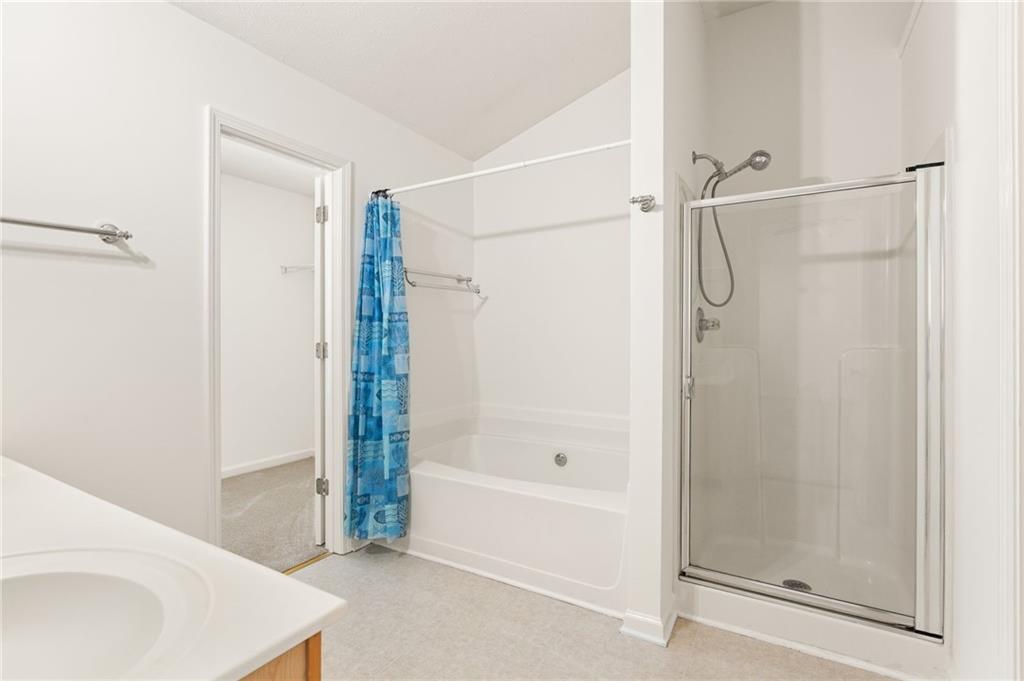 Bathroom with a white bathtub, blue patterned curtain, and separate glass-enclosed shower.