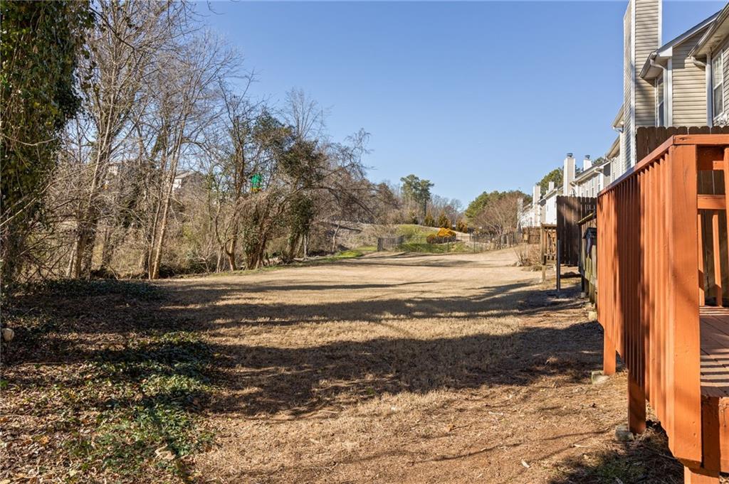 Grassy yard beside attached homes, with raised wooden decks and a border of leafless trees.