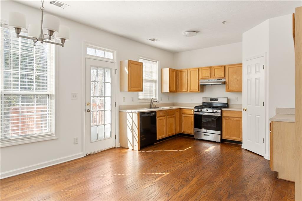 Kitchen with honey-toned cabinets, stainless range, and hardwood floors.