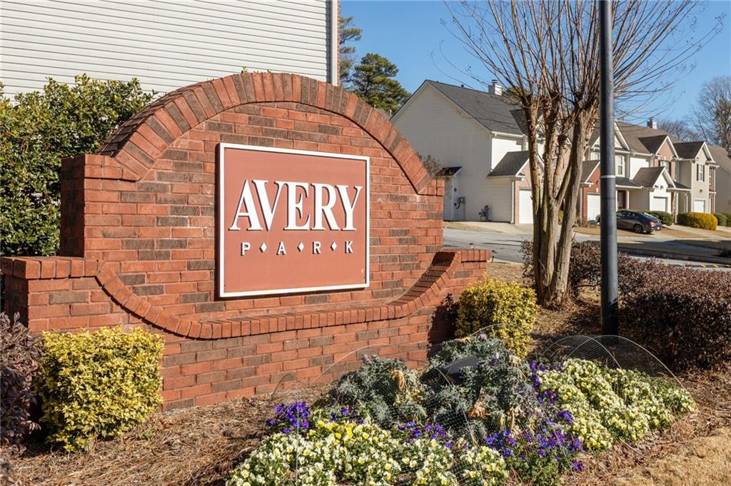 Avery Park neighborhood entrance sign beside landscaped flower beds and townhomes.