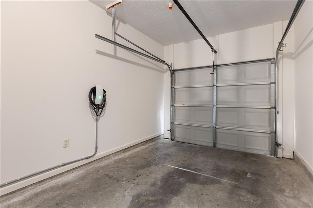 Empty garage with a closed overhead door and a wall-mounted electric vehicle charger.