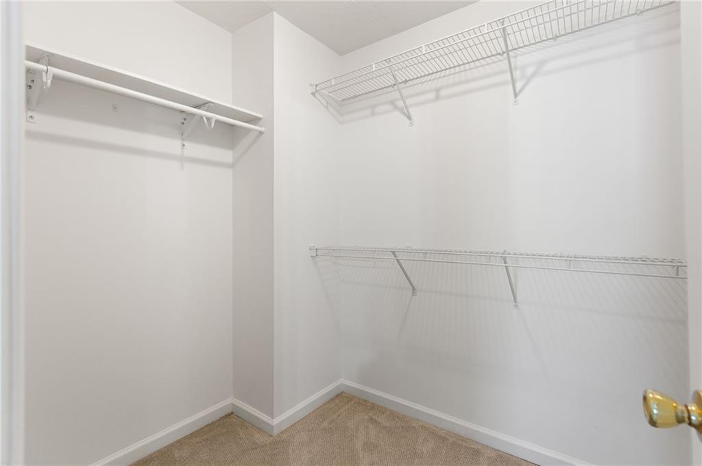 Empty walk-in closet with wire shelving and beige carpet.