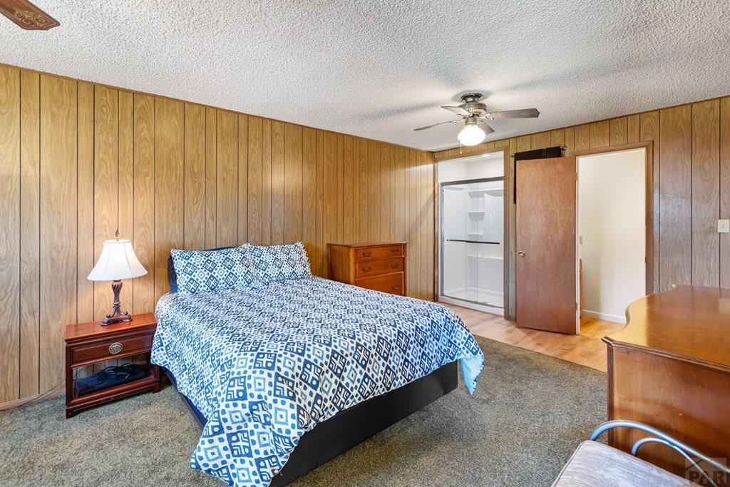 Bedroom with blue-and-white patterned bedding, wood-paneled walls, and an open closet.