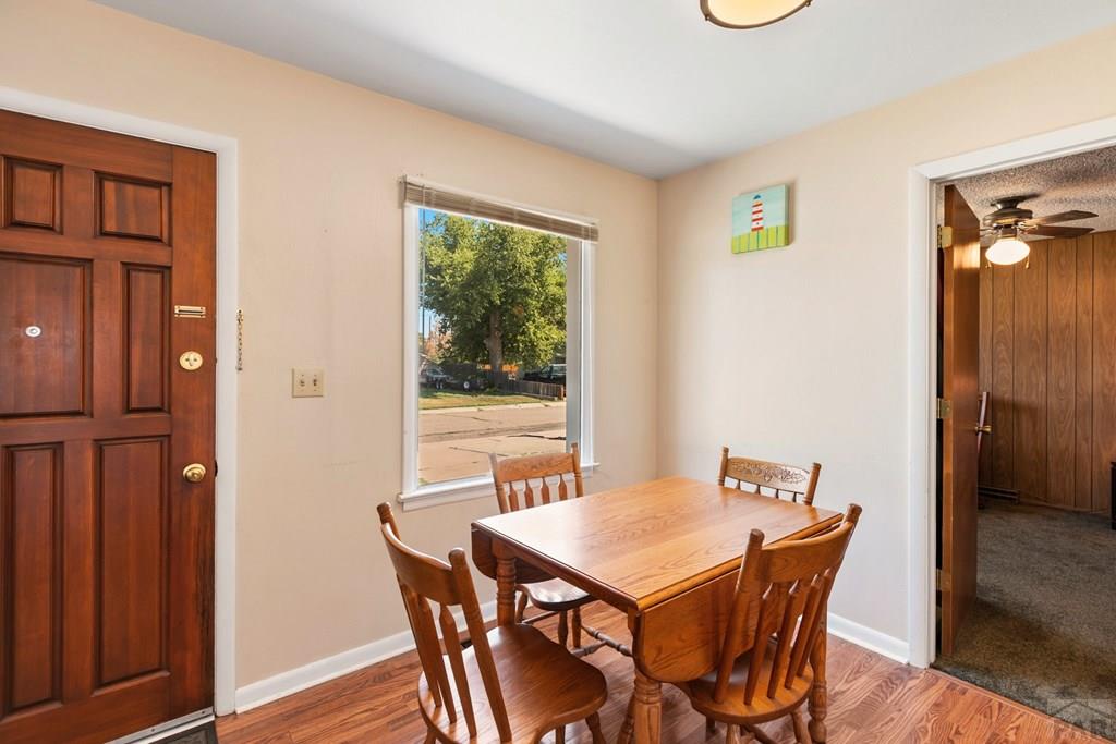Dining area with a wooden table and chairs beside a window overlooking the street.