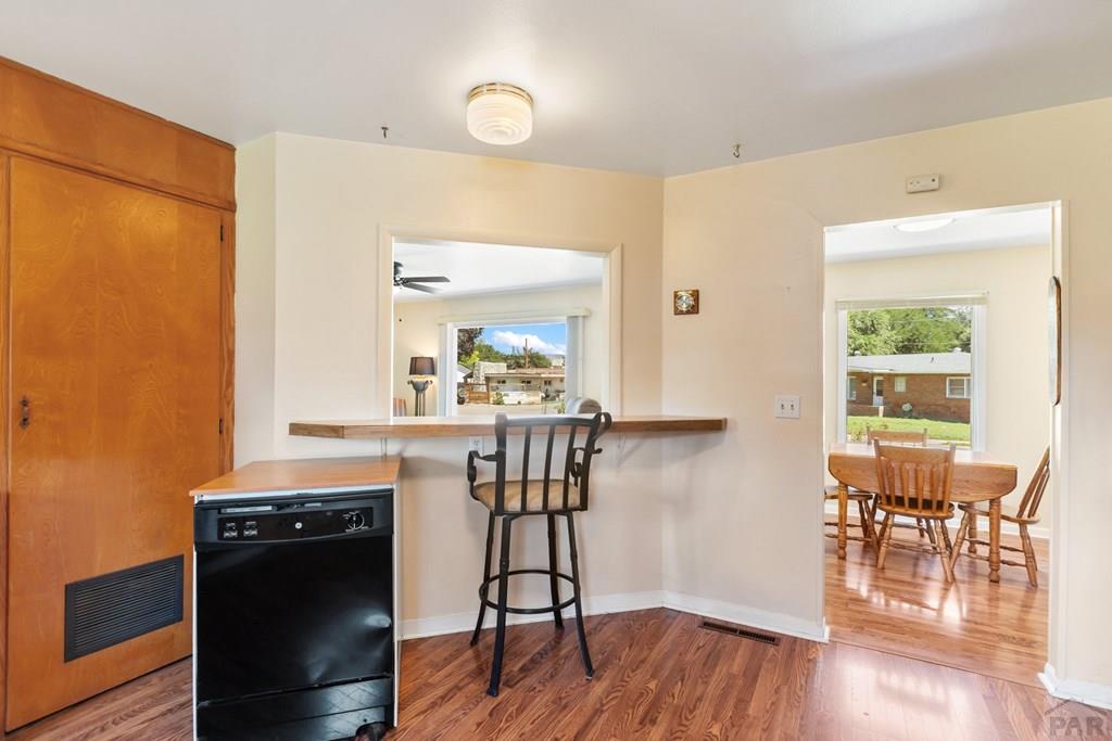 Kitchen breakfast bar opening to a dining room with hardwood floors and wooden cabinetry.