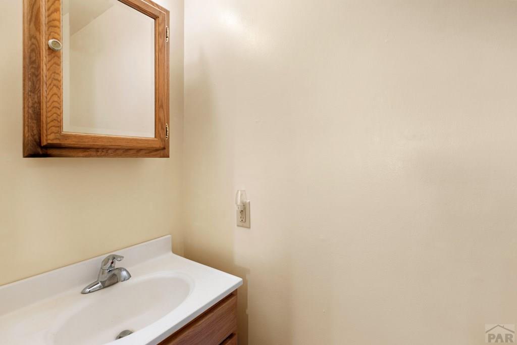 Bathroom vanity with a white sink, chrome faucet, and wood-framed mirrored cabinet.