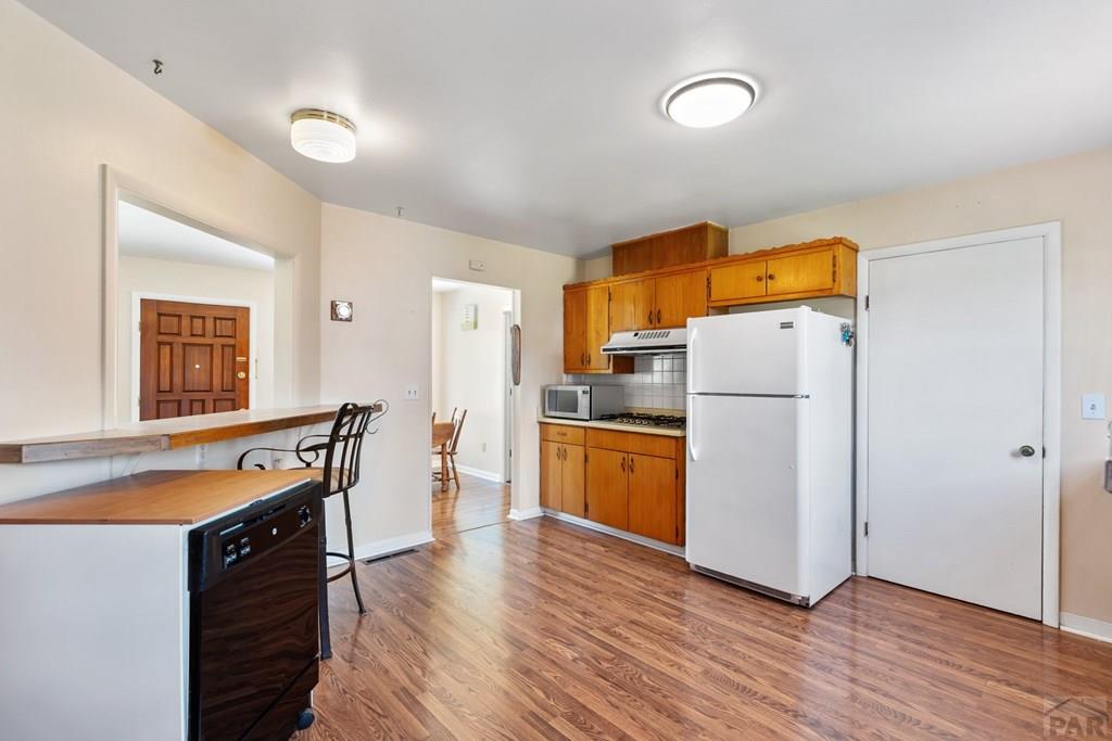 Kitchen with wood cabinets, white refrigerator, and breakfast counter with stools.
