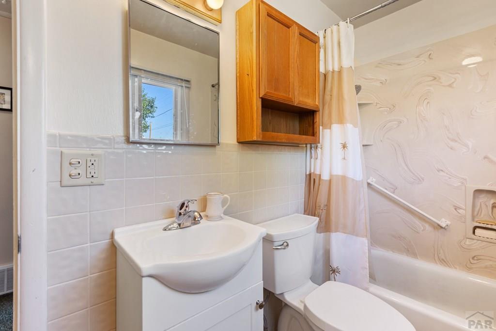 Bathroom with a white vanity and tub behind a palm-patterned shower curtain.
