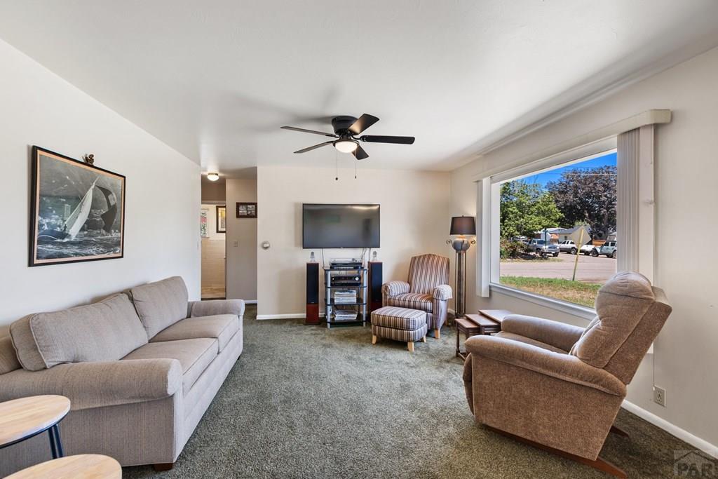 Furnished living room with a large street-facing window, sofa, armchairs, and television.