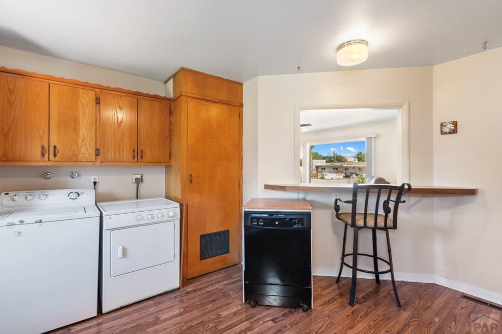 Laundry room with oak cabinets, washer and dryer, and a pass-through counter with a bar stool.