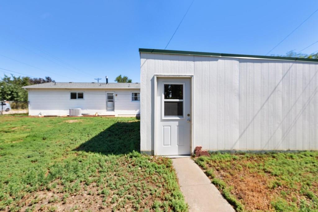 White single-story home and outbuilding with a concrete walkway across the lawn.
